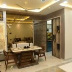 4 seater wooden dining table view interior design showing entry to kitchen and bedroom. Recessed light in false ceiling.